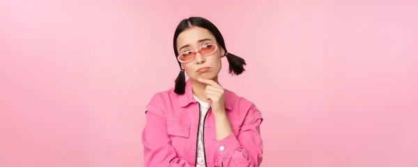 Portrait of sad and gloomy asian girl sulking from disappointment, standing upset against pink studio background — Stock Photo, Image