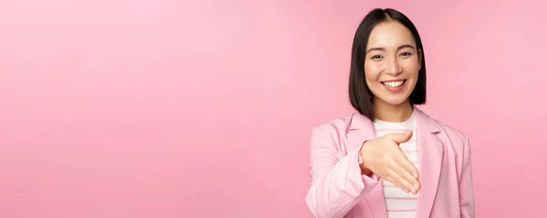 Portrait de femme d'affaires souriante et agréable serrant la main d'un partenaire d'affaires, poignée de main, tendre la main et dire bonjour, debout sur fond rose — Photo