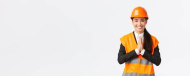 Minnettar Asyalı bayan mimar müşterilerin inancı, el ele tutuşmak, birine teşekkür etmek, güvenlik kaskı ve ceketi giymek, beyaz arka planda durmak, her şeyi takdir etmek.