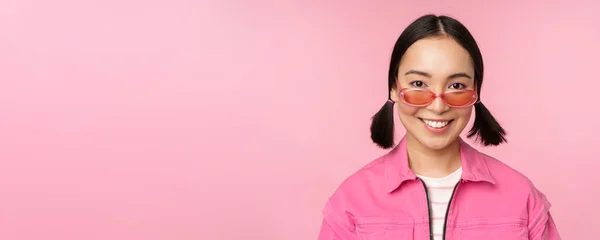 Κοντινό πλάνο της κομψής Κορεάτισσας με γυαλιά ηλίου, χαμογελώντας χαρούμενη, ποζάροντας σε ροζ φόντο. Οι άνθρωποι αντιμετωπίζουν την ιδέα — Φωτογραφία Αρχείου