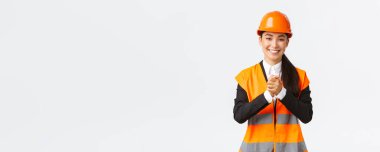 Minnettar başarılı Asyalı kadın mimar inşaat alanındaki yatırımcıları ya da müşterileri selamlar, güvenlik kaskı ve ceketi giyer, minnettarlık içinde sıkıca el sıkışır, güvene minnettar olur.