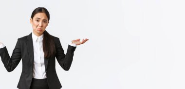 Hiçbir şeyden haberi olmayan Asyalı genç bir ofis çalışanı, siyah takım elbiseli bir yönetici, elleri yana açık omuz silkiyor ve habersiz somurtuyor, anlamıyorum, işe yaramaz ve kararsız duruyor.