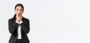 Endişeli Asyalı iş kadını sıkıntılı bir durumla karşı karşıya, çenesini indir ve kameraya bak, ne yapacağını bilmiyor, panikliyor ve titriyor, beyaz arka planda duruyor.