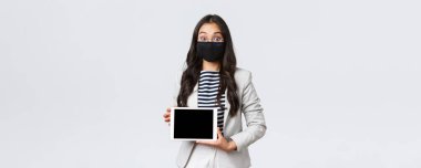 İş, finans ve istihdam, virüsü önleyen covid-19 ve sosyal uzaklık kavramı. Yüz maskeli ve gözlüklü heyecanlı Asyalı iş kadını şaşırmış, dijital tablet ekranını gösteriyor.