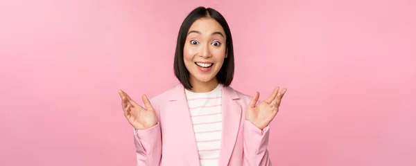 Porträt einer asiatischen Geschäftsfrau, die überrascht in die Kamera schaut, in die Hände klatscht und aufgeregt starrt, lächelnd vor rosa Hintergrund posiert — Stockfoto
