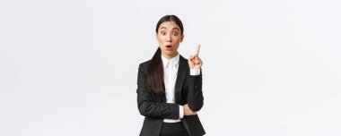 Şaşırmış zeki Asyalı kadın girişimci, inşaat müdürünün büyük bir planı var. Çözüm önermek için parmağını kaldırıyor, düşüncelerini ve fikirlerini grupla paylaşıyor, beyaz arka planda duruyor.