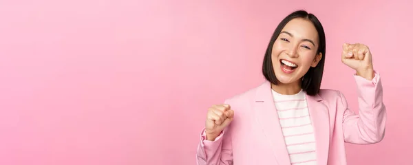 Entusiasta mujer corporativa asiática, mujer de negocios levantando la mano y animando, triunfando, ganando y celebrando, de pie sobre fondo rosa —  Fotos de Stock