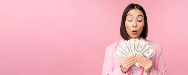 金融、マイクロクレジット、人々の概念。幸せな笑顔アジアの実業家は、ピンクの背景に訴訟に立って、ドルのお金を示す — ストック写真