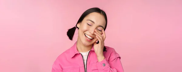 Close up ritratto di bella ragazza asiatica cercando entusiasta e sorridente, ridendo e sorridendo, in piedi felice sullo sfondo rosa — Foto Stock