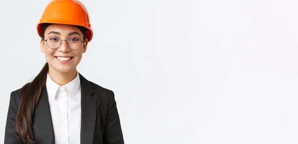 Close-up van glimlachende professionele Aziatische vrouwelijke ingenieur, zakenvrouw in pak en veiligheidshelm met inspectie in de fabriek, op zoek naar vertrouwen en blij, staande witte achtergrond — Stockfoto