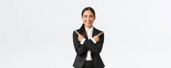 A jóképű ázsiai üzletasszony két választást javasol. Vonzó üzletasszony fekete öltöny ujjal mutogatott oldalra, kevés változatban, segít a döntéshozatalban, álló fehér háttér — Stock Fotó