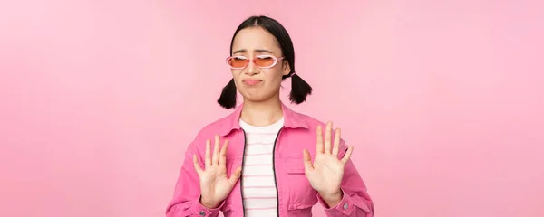 Nee, bedankt. Walgelijk aziatisch meisje in een zonnebril, smth afwijzen, handen schudden om te weigeren, verval, over een roze achtergrond staan — Stockfoto