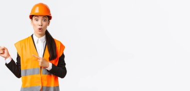 İnşaat, inşaat ve endüstriyel konsept. Sol üst köşeyi işaret eden Asyalı kadın mühendis şaşırdı ve etkilendi. Emlakçı yolu gösteriyor, ilginç projeyi tartışıyor, beyaz arkaplan