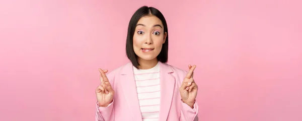 Lycklig lycklig affärskvinna, asiatisk företagskvinna önskar, önskar, hoppas på smth och be, står i kostym över rosa bakgrund — Stockfoto