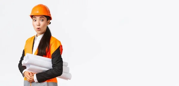 Surpris et excité asiatique femme architecte en chef dans le casque de sécurité et veste réfléchissante, visiter la zone de construction avec le plan directeur, l'air amusé, écouter suggestion intéressante du gestionnaire — Photo