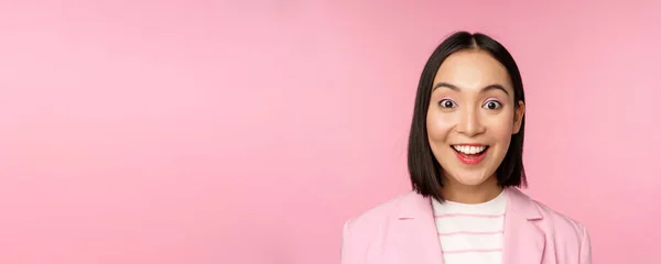 Крупним планом портрет азіатської корпоративної жінки, бізнес-леді виглядає здивованою і здивованою на камеру, стоїть в костюмі на рожевому фоні — стокове фото