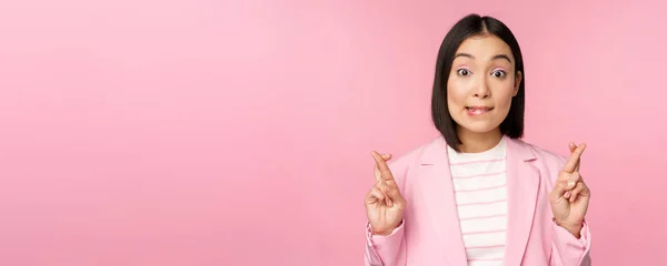 Feliz afortunada empresaria, asiática dama corporativa deseando, pidiendo deseo, esperando smth y orando, de pie en traje sobre fondo rosa — Foto de Stock