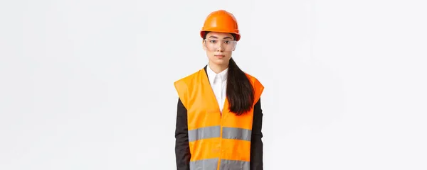 Komoly kinézetű, profi női építőmérnök, építész az építkezésen, egyenruhát visel, védősisak az öltönyön, fehér háttér, vállalkozás ellenőrzése — Stock Fotó