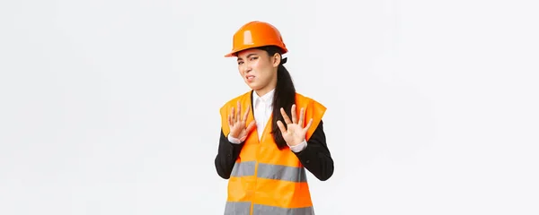 Modstræbende og utilfreds asiatisk kvindelig ingeniør nægter at lytte, viser stop, forbyder gestus, afviser generende tilbud, irriteret med klæbende projektleder, hvid baggrund - Stock-foto