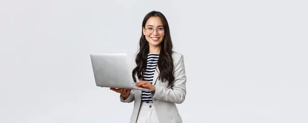 Negocios, finanzas y empleo, concepto de emprendedoras exitosas. Confiado sonriente mujer de negocios asiática, trabajador de oficina en traje blanco y gafas usando el ordenador portátil, ayudar a los clientes —  Fotos de Stock