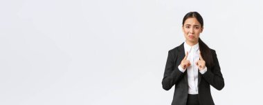 Asyalı satış elemanı küçük beden diye şikayet ediyor. Bayan ofis müdürü hoşnutsuz görünüyor ve küçük, küçük ve hayal kırıklığı yaratan beyaz bir arka plan gösteriyor.