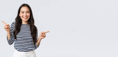 Yaşam tarzı, güzellik ve moda, insanların duygu konsepti. Kararsız Koreli kızın seçiminde yardıma ihtiyacı var, parmaklarını yana doğru gösteriyor, sağlı sollu ürünleri gösteriyor, karar veriyor.