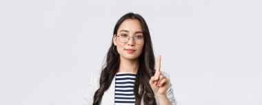 Finans ve istihdam, başarılı kadın girişimciler konsepti. Zeki stil sahibi iş kadınının yakın plan çekimi, Asyalı müdür işin ilk kuralını açıklıyor, tek parmağını gösterip gülümsüyor.