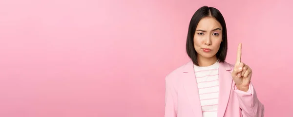 Asiatica donna d'affari con gravi, preoccupato espressione del viso, mostrando stop motion, tabù, proibire gesto, disapprovare smth male, in piedi su sfondo rosa — Foto Stock