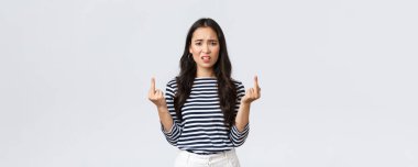 Lifestyle, beauty and fashion, people emotions concept. Annoyed pissed-off asian woman stare bothered and displeased, showing middle-fingers careless what people say, white background