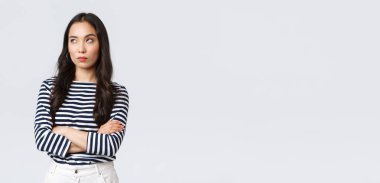 Yaşam tarzı, güzellik ve moda, insanların duygu konsepti. Kızgın ve ilgisiz Asyalı kadın gözlerini devirmiş, sıkılmış ve sıkılmış, kollarını kavuşturmuş, beyaz arka planda duruyor.