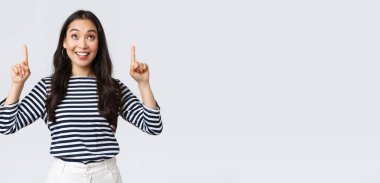 Yaşam tarzı, insanların duygu konsepti. Heyecanlı, yakışıklı, gülümseyen Asyalı kız mükemmel bir ürün bulduğundan memnun olmuş, reklamları işaret ediyor ve memnun görünüyor, tanıtım öneriyor.