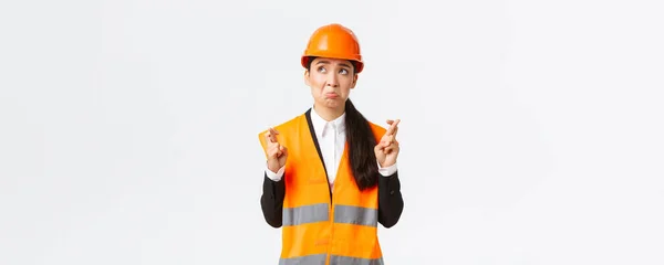 Triste nerveux et peu confiant asiatique femme gestionnaire de la construction dans le casque de sécurité, la mousse et regarder dans le coin supérieur gauche panique, faire vœu, croix des doigts bonne chance, plaidoyer sur fond blanc — Photo