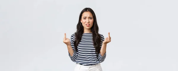 Lifestyle, beauty and fashion, people emotions concept. Annoyed pissed-off asian woman stare bothered and displeased, showing middle-fingers careless what people say, white background — ストック写真