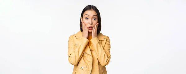 Bild der asiatischen Frau, die überrascht, erstaunt reagiert, schockiert Gesicht, steht über weißem Hintergrund — Stockfoto