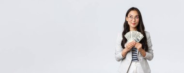 İş, finans ve istihdam, girişimci ve para kavramı. Hayalperest iş kadını nereye tatile gideceğini düşünüyor ve nasıl para kazanacağını düşünüyor, nakit tutuyor ve düşünceli bir iş kadını arıyor.