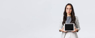 İş, finans ve istihdam, başarılı kadın girişimciler konsepti. Ciddi görünümlü ofis müdürü, Asyalı bayan çalışan dijital tablet ekranda ürününü tanıtıyor.