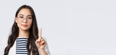 Finans ve istihdam, başarılı kadın girişimciler konsepti. Zeki stil sahibi iş kadınının yakın plan çekimi, Asyalı müdür işin ilk kuralını açıklıyor, tek parmağını gösterip gülümsüyor.