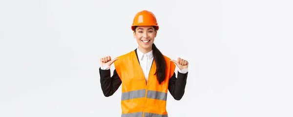 Úspěšně se usmívající asijská stavební manažerka, inženýrka v bezpečnostní přilbě ukazující na sebe, se předvádí. Architekt doporučuje osobní asistenci, chvástání úspěchy — Stock fotografie