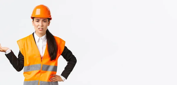 ¿Y qué? ¿Qué pasa? Frustrado y decepcionado asiático mujer jefe ingeniero quejándose de los empleados, regañando a alguien, usar chaqueta reflectante y casco de seguridad, levantando la mano confundido — Foto de Stock