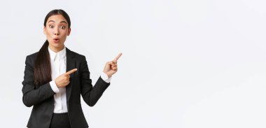 Etkilenmiş ve meraklı Asyalı bayan girişimci proje hakkında soru soruyor. Siyah takım elbiseli bir iş kadını ürünle ilgili tüm detayları öğrenmek için parmaklarını işaret ediyor.