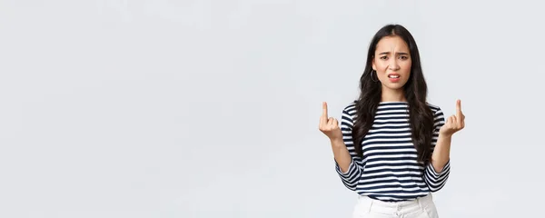 Lifestyle, beauty and fashion, people emotions concept. Annoyed pissed-off asian woman stare bothered and displeased, showing middle-fingers careless what people say, white background — Stok fotoğraf