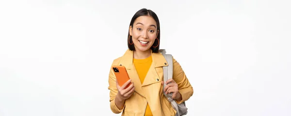 幸せな女の子旅行者、スマートフォンを見てバックパックを持つ観光客のイメージ、携帯電話ルートアプリを使用して、白い背景の上に立って — ストック写真