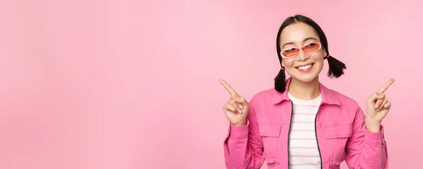 Wahl. Stilvolles koreanisches Mädchen, asiatisches weibliches Modell zeigt Finger seitlich, zeigt zwei Varianten, Produktwerbung, Vorführgegenstände, steht über rosa Hintergrund — Stockfoto