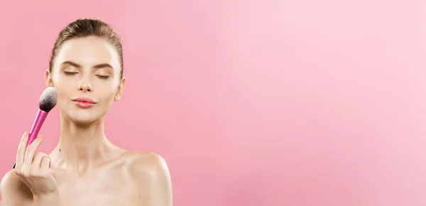 Beauty koncept - detailní krásná Kavkazský žena použití make-up s kosmetický štětec na pudr. Dokonalá pleť. Izolované na růžové pozadí a kopie prostoru. — Stock fotografie