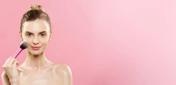 Beauty koncept - detailní krásná Kavkazský žena použití make-up s kosmetický štětec na pudr. Dokonalá pleť. Izolované na růžové pozadí a kopie prostoru. — Stock fotografie