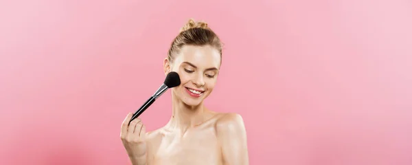 Beauty koncept - detailní krásná Kavkazský žena použití make-up s kosmetický štětec na pudr. Dokonalá pleť. Izolované na růžové pozadí a kopie prostoru. — Stock fotografie