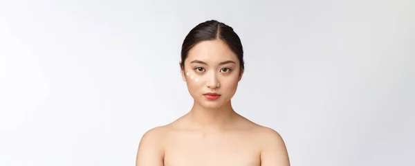 Bőrápoló szépségkirálynő. Szépségápoló nő mosolygós alkalmazása krém. Szépség portré gyönyörű ázsiai kaukázusi női modell elszigetelt fehér. — Stock Fotó