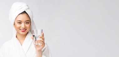 Sağlıklı, su içen genç, güzel bir kadın. Yüzü doğal makyajlı, beyaz arka planda soyutlanmış..