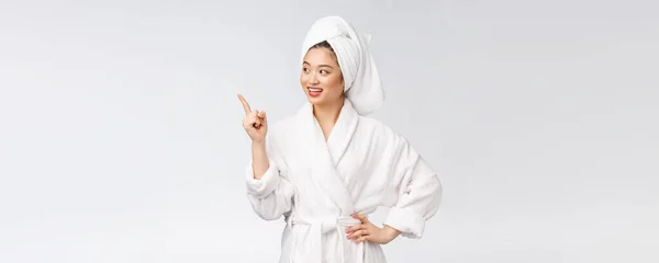 Skönhetsporträtt av ung kvinna som visar och pekar finger åt tomt kopieringsutrymme, asiatisk skönhet i badrock. — Stockfoto