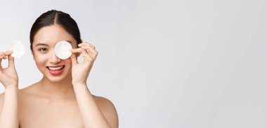 Cilt bakımı yapan kadın yüz makyajını pamuklu bezle temizliyor. Cilt bakımı konsepti. Mükemmel ciltli güzel melez ırk modelinin yüz görüntüsü..